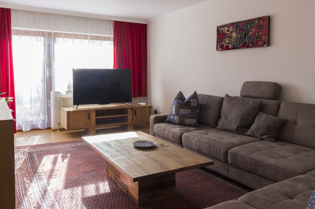 Wohnzimmer mit Ecksofa, Fernsehtisch und Flachbildschirm-TV