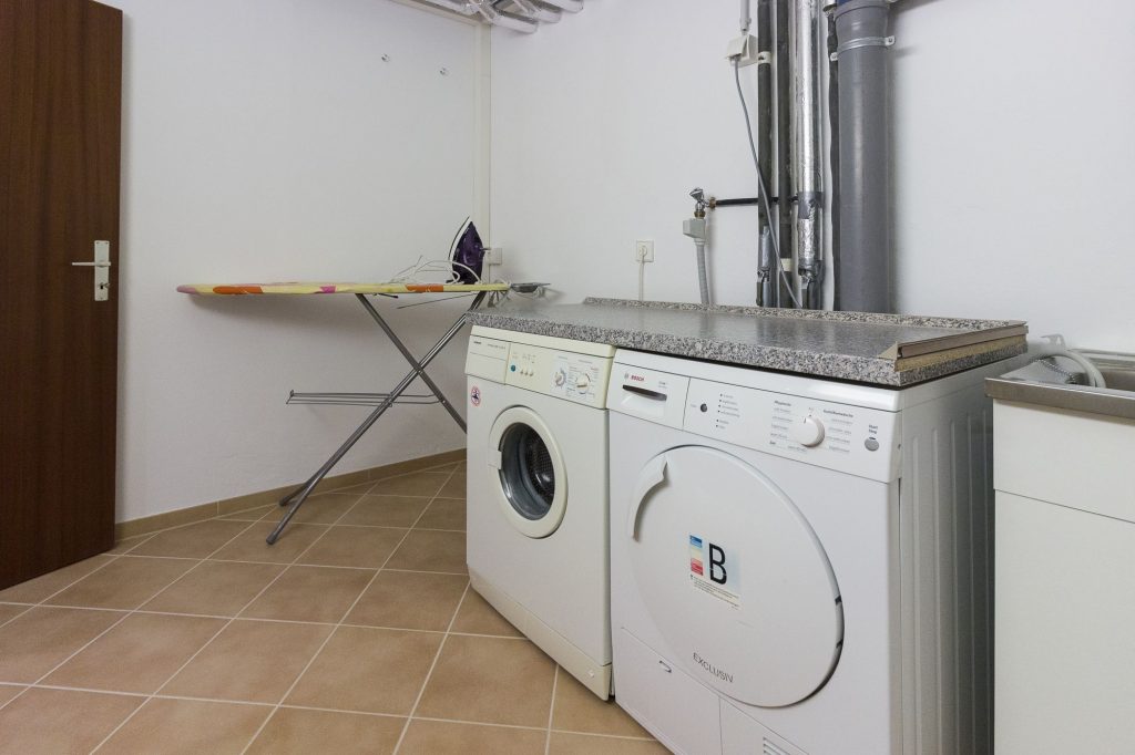 Wasch- und Trockenraum mit Waschmaschine, Trockner, Bügelbrett und Bügeleisen, Ablage